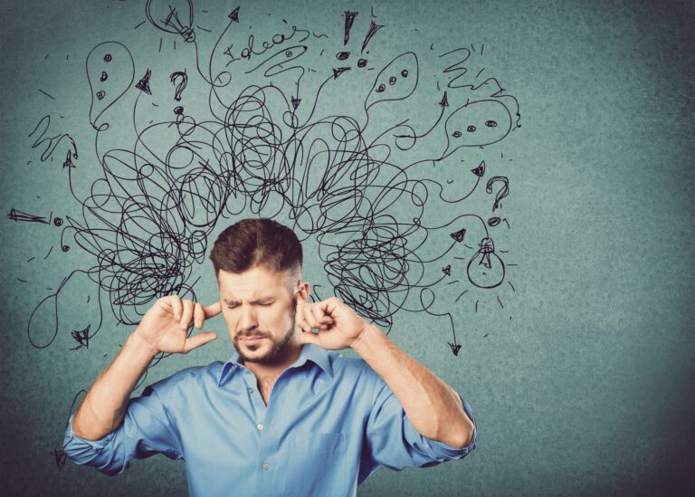 Hochsensibilitaet.jpg Ein Mann in einem blauen Hemd hält sich die Ohren zu, während verworrene Gedanken und Symbole über seinem Kopf schweben.