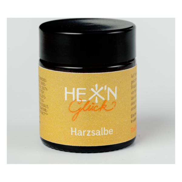 Schwarzes Tiegelchen mit gelbem Etikett für Harzsalbe, beschriftet mit "HEX' N Glück".